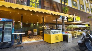 A restaurant with a yellow exterior, a Pepsi refrigerator, and outdoor seating. - Fountain Tree by TGI (Bengaluru)