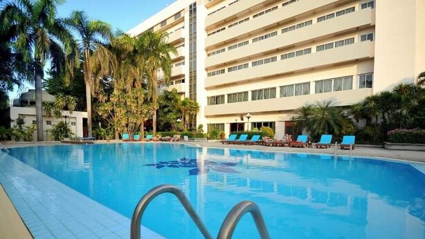 Una piscina con sillones de descanso y palmeras.