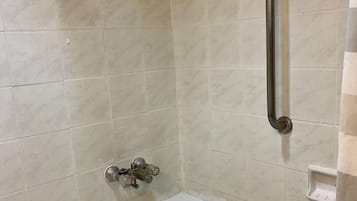 Un bagno con una vasca da bagno bianca, un soffione a mano e un maniglione fissato al muro.