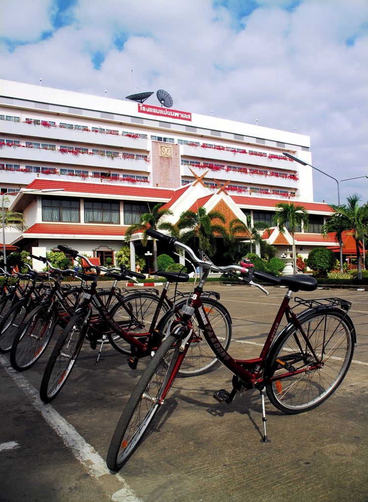 Un hôtel à étages, un espace de stationnement avec des supports à vélos et un bâtiment aux couleurs rouge et blanc.