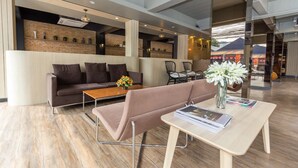 Um hall moderno com um sofá, cadeiras, uma mesa de centro e um vaso de flores.