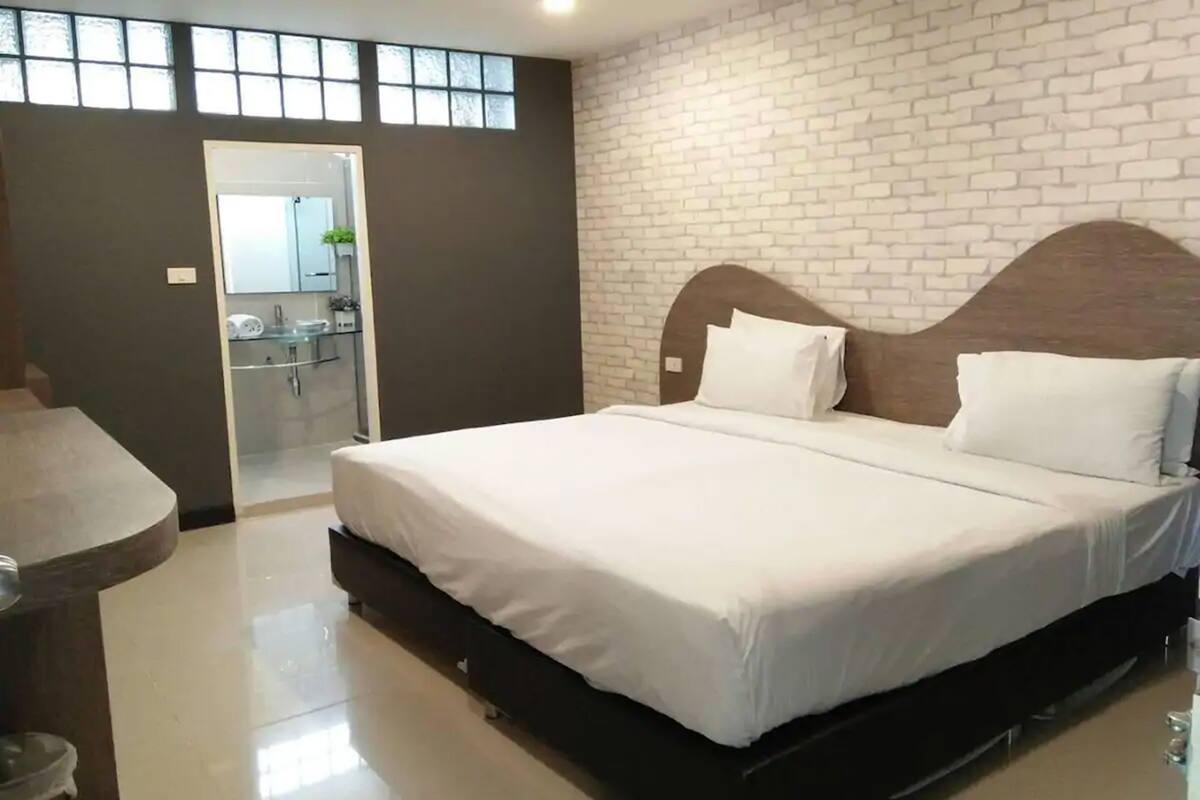 Une chambre à coucher moderne avec un grand lit, une table de chevet aux lignes courbes et un miroir encastré.