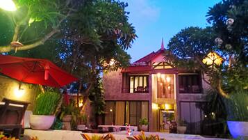 A building with a red roof, multiple windows, and outdoor seating.
