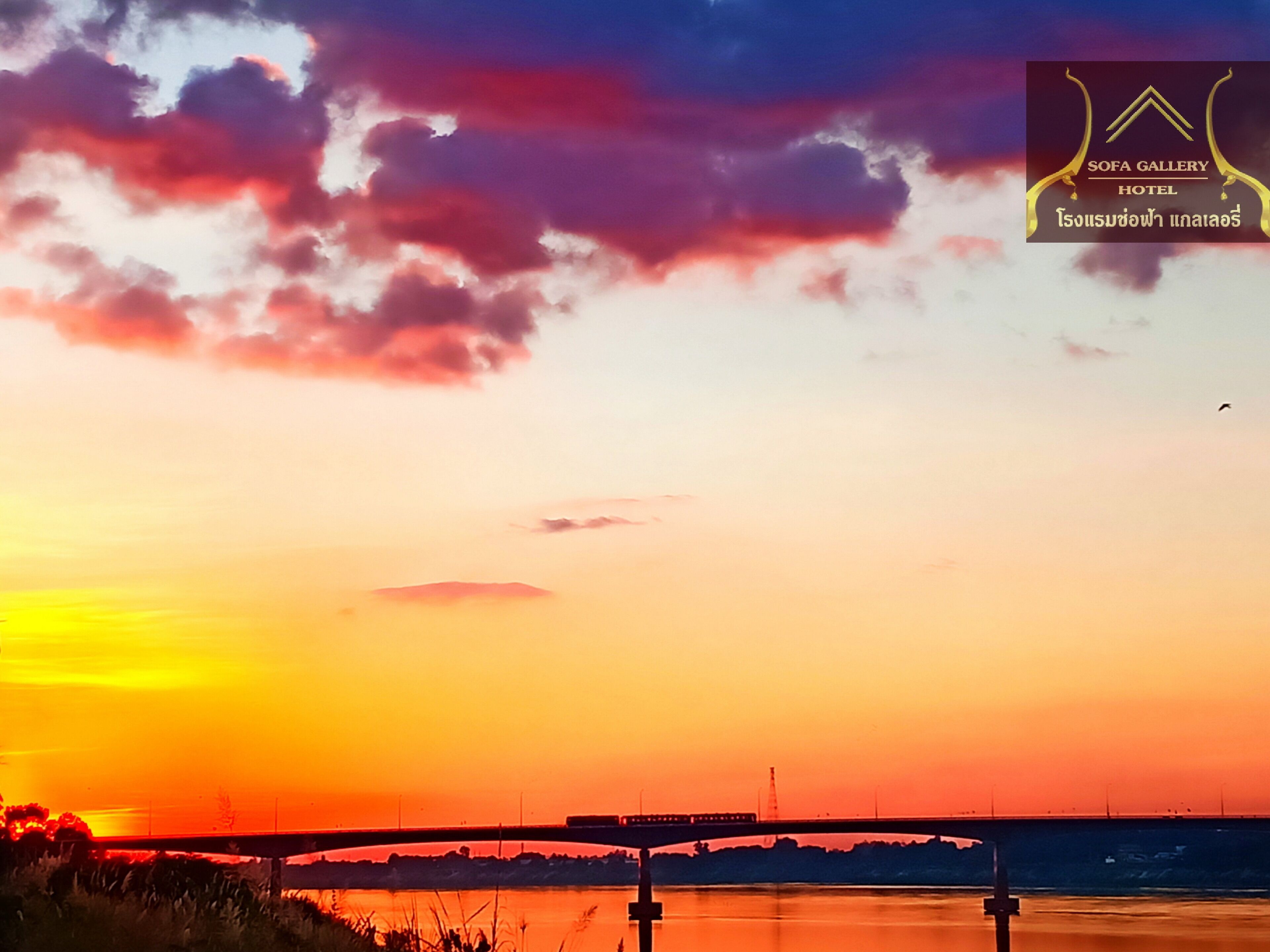A sunset over a river with a bridge, and a logo for SOFA GALLERY HOTEL in the top right corner.