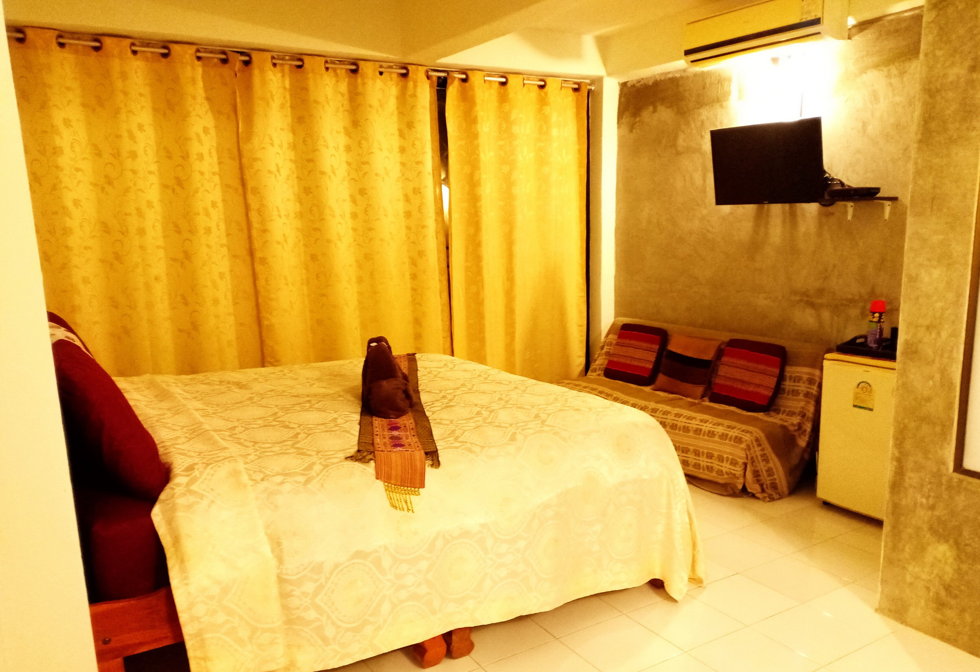 A hotel room with a bed, a TV mounted on the wall, and a small bedside table.