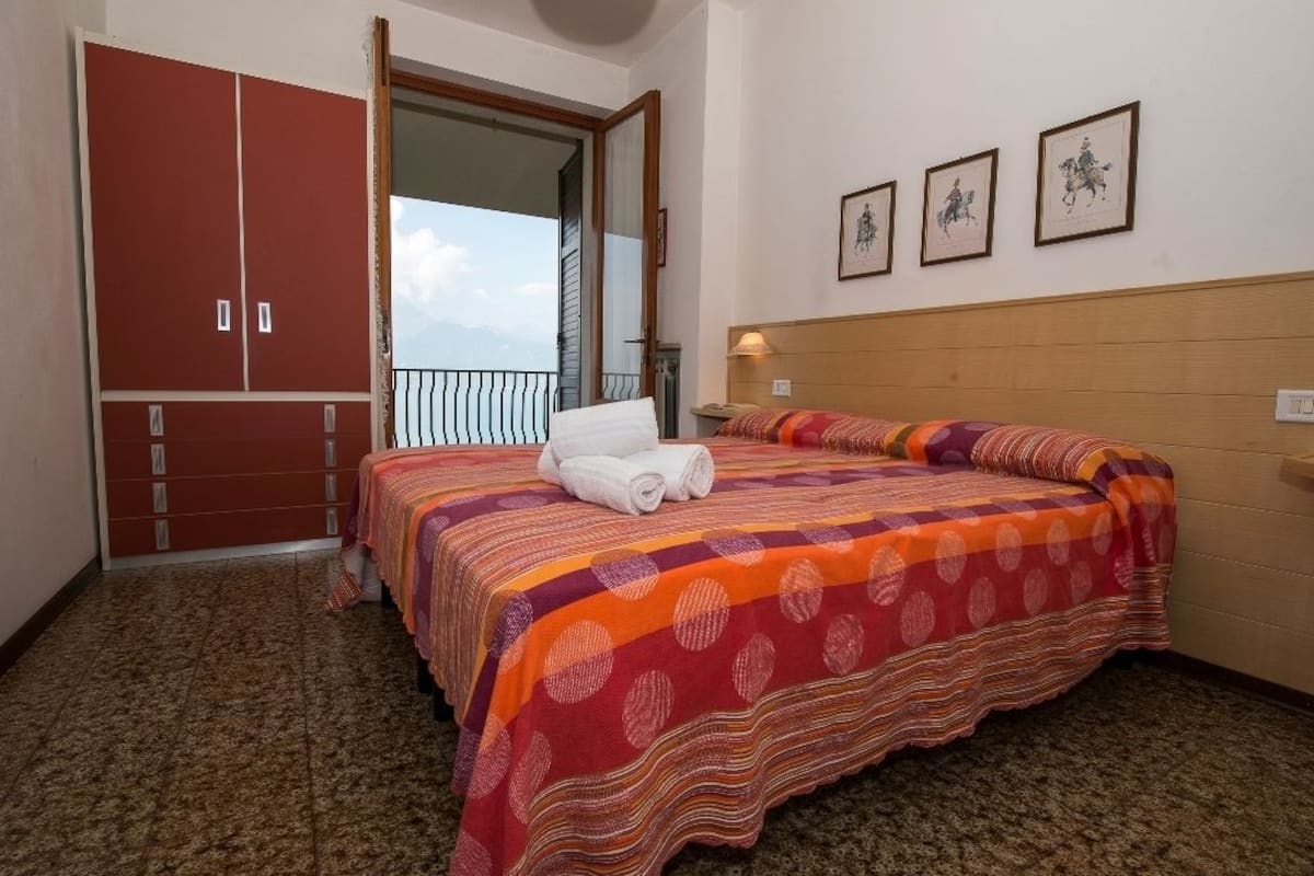 Un dormitorio con cama, armario y balcón con vistas.