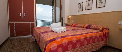 A bedroom with a bed, a wardrobe, and a balcony with a view.