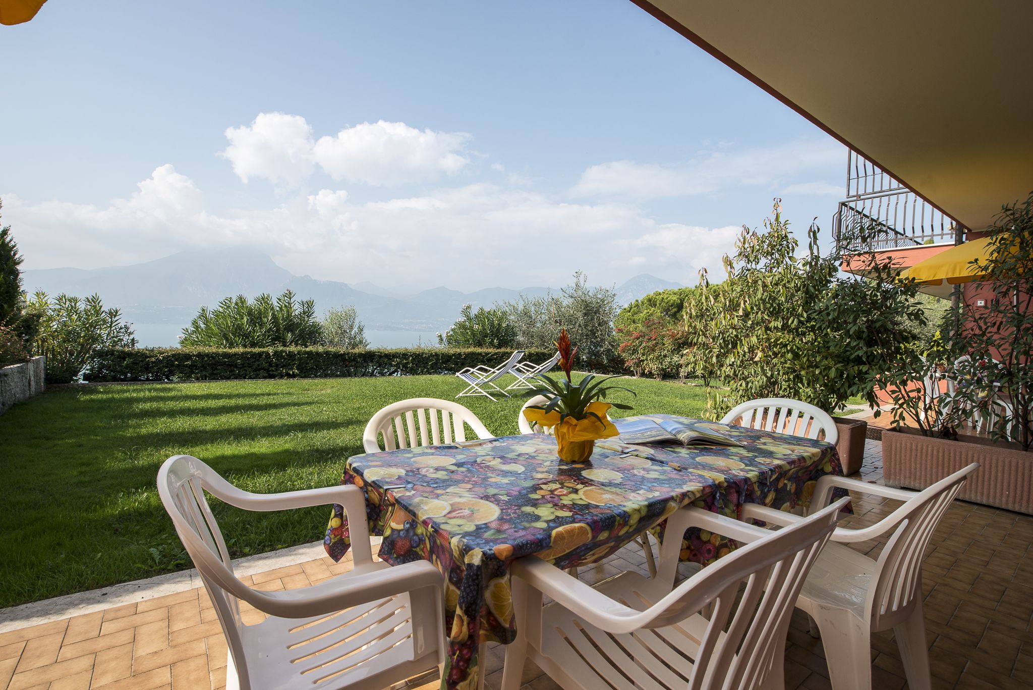 An outdoor patio with a table and chairs, a potted plant, and a view of mountains.