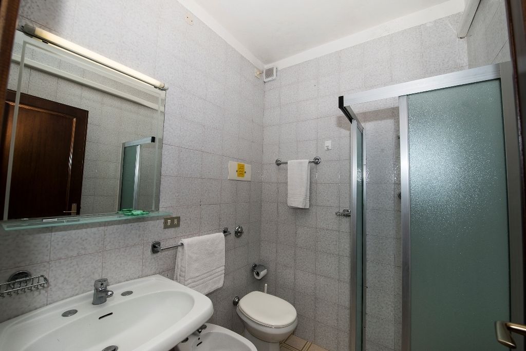 A bathroom with a sink, toilet, and glass shower enclosure.