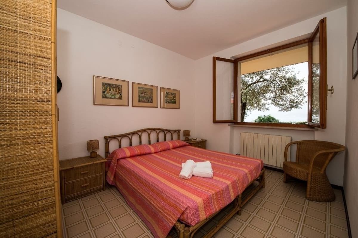 Un dormitorio con una cama, una silla, un ventanal y tres cuadros en la pared.