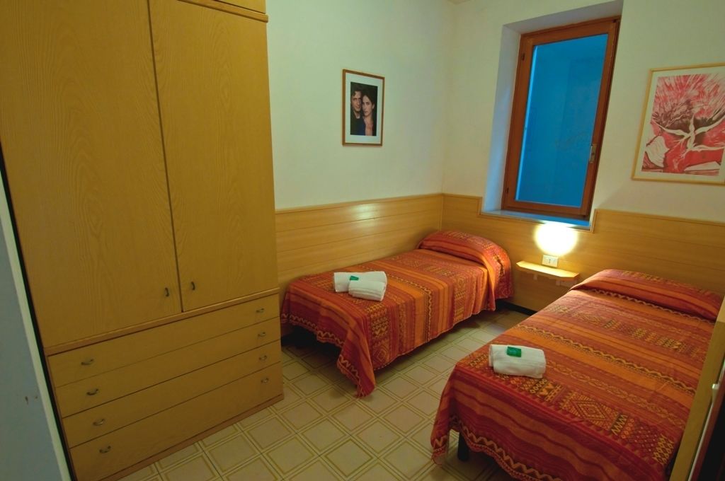 Un dormitorio con dos camas, un armario de madera y una ventana que ofrece vistas azules.