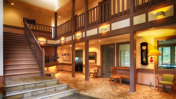 A spacious interior with a stone-floored staircase, wooden railings, and a seating area with a bench and chairs. - Hatago SAKURAYA (Yamanakako)
