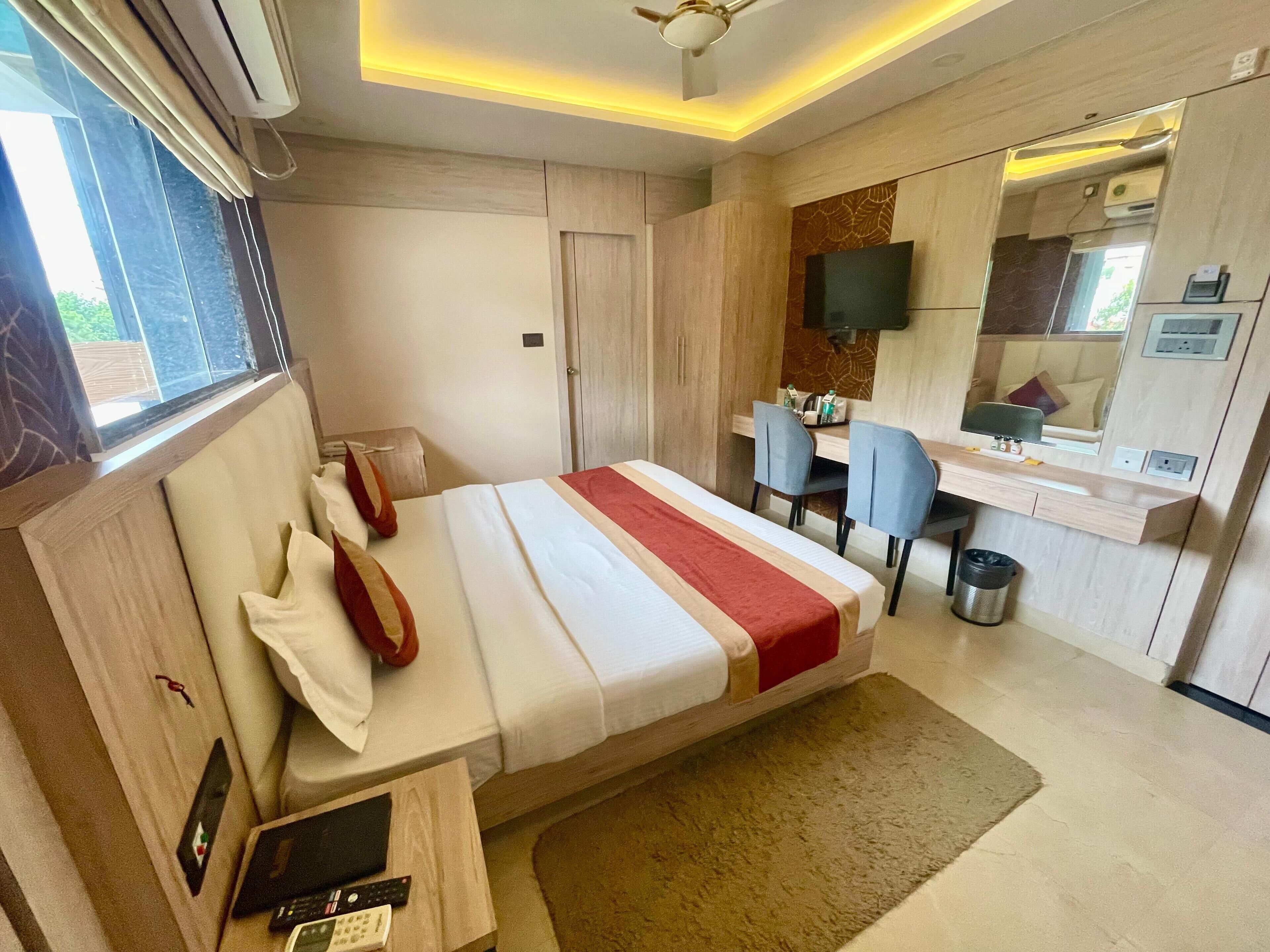 A modern hotel room with a bed, desk, and seating area.
