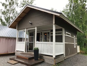 Situated among trees, this cabin features a covered porch and large windows.