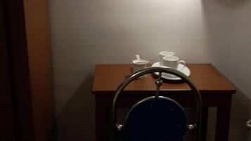 A small room with a wooden table, a blue chair, and a wall-mounted lamp.