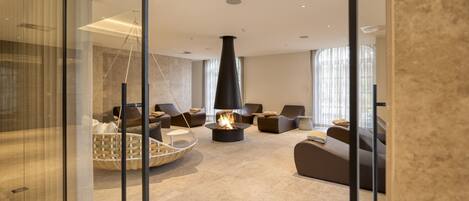 A modern living room with a fireplace, comfortable seating, and large windows.