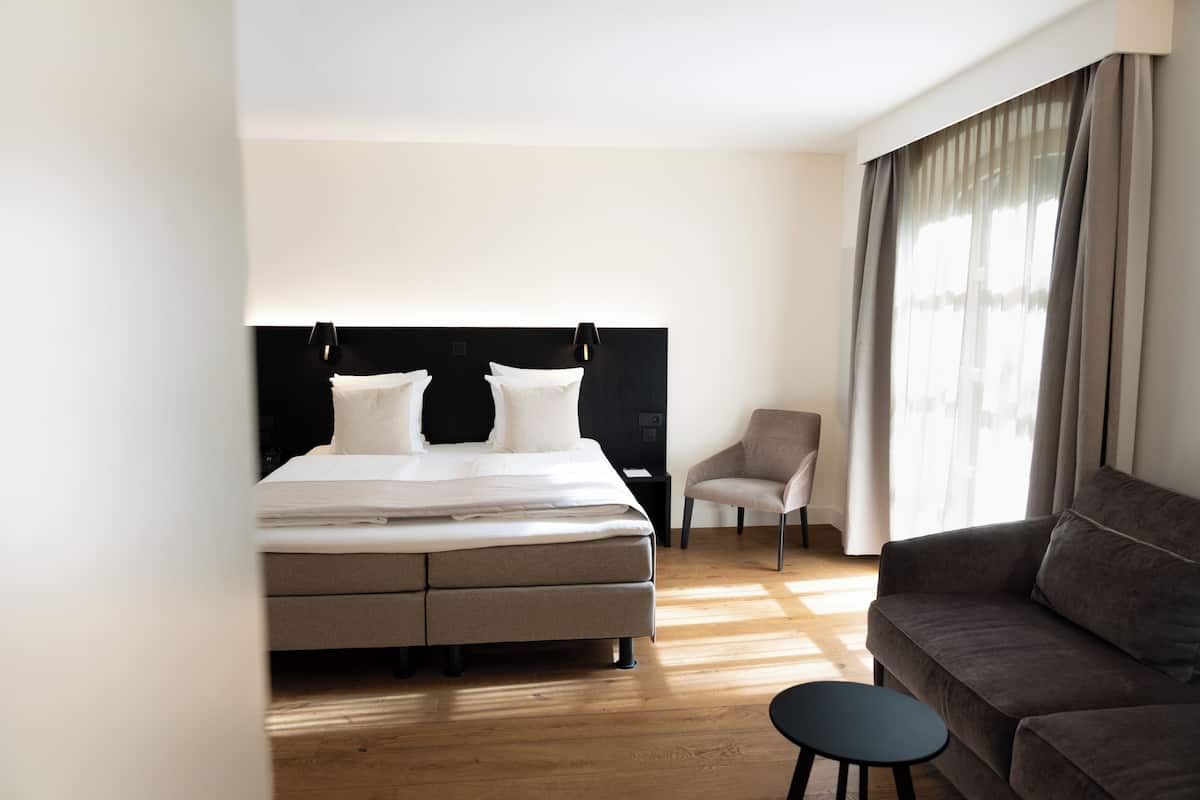 Una habitación de hotel moderna con una cama, un sofá, una silla y una mesita.