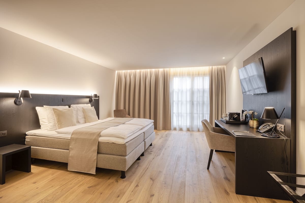 Una habitación de hotel moderna con cama, escritorio y televisor.