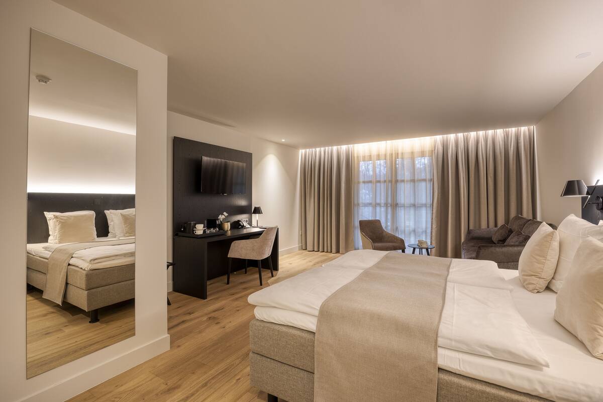 Una habitación de hotel moderna con una cama grande, un escritorio, una silla y un sofá.