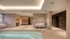 Un moderno espacio de spa con piscina, un sofá y una silla de masaje.