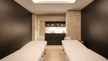 A modern spa room with two treatment beds, a reception desk, and a ceiling light.