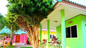 A brightly colored building with a green facade, a wooden door, and a window with shutters. - Khunya Resort Riverkwai (Kanchanaburi)
