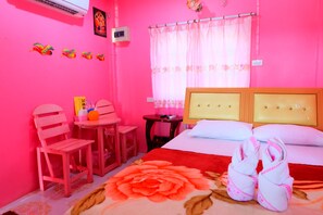 Una habitación con decoración rosa, una cama, una mesita, sillas y un tapete decorativo.