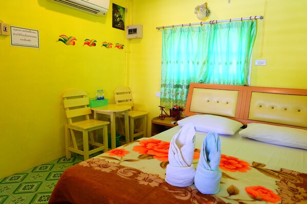 A room with a bed, two chairs, a small table, and a curtain.