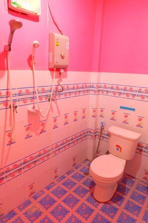 A bathroom with a pink and blue floral tile pattern, a white toilet, and a shower with a control panel. - Khunya Resort Riverkwai (Kanchanaburi)