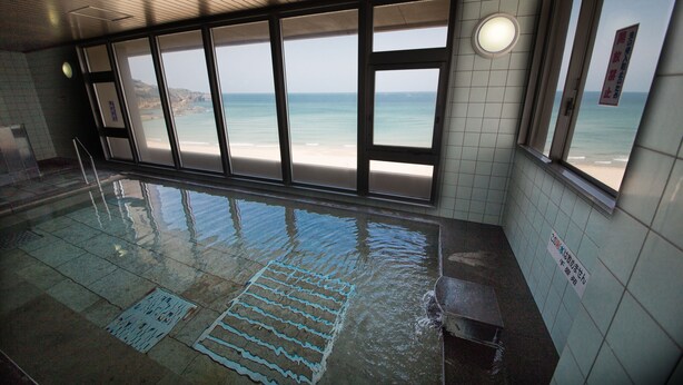 Una piscina interior con vistas despejadas a la playa a través de amplios ventanales.