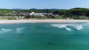 Una zona costera con playa y un conjunto de edificios al fondo.