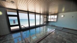 Una piscina con vista a la playa, paredes enlosadas y techo de madera.