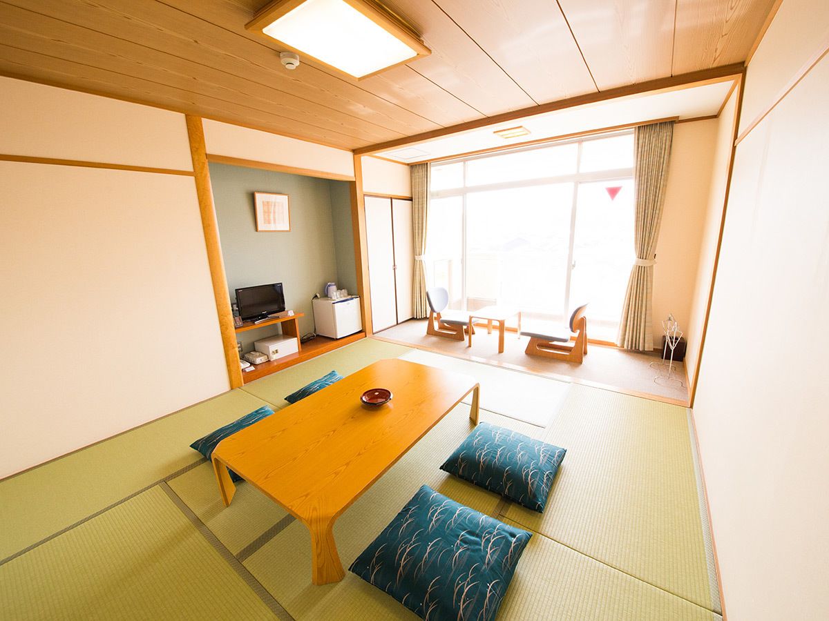 Una habitación japonesa tradicional con suelo de tatami, una mesa de madera baja y cojines.