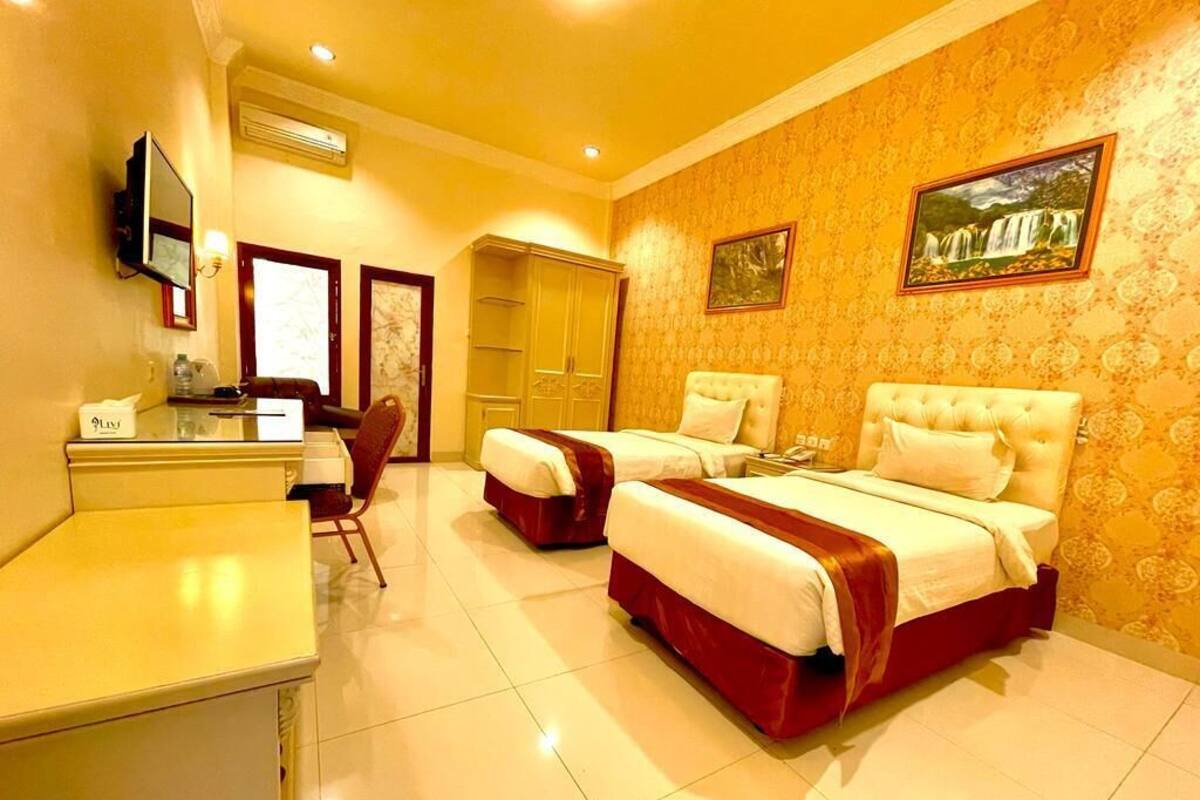 A hotel room with two beds, a desk, a chair, a television, and a wardrobe.