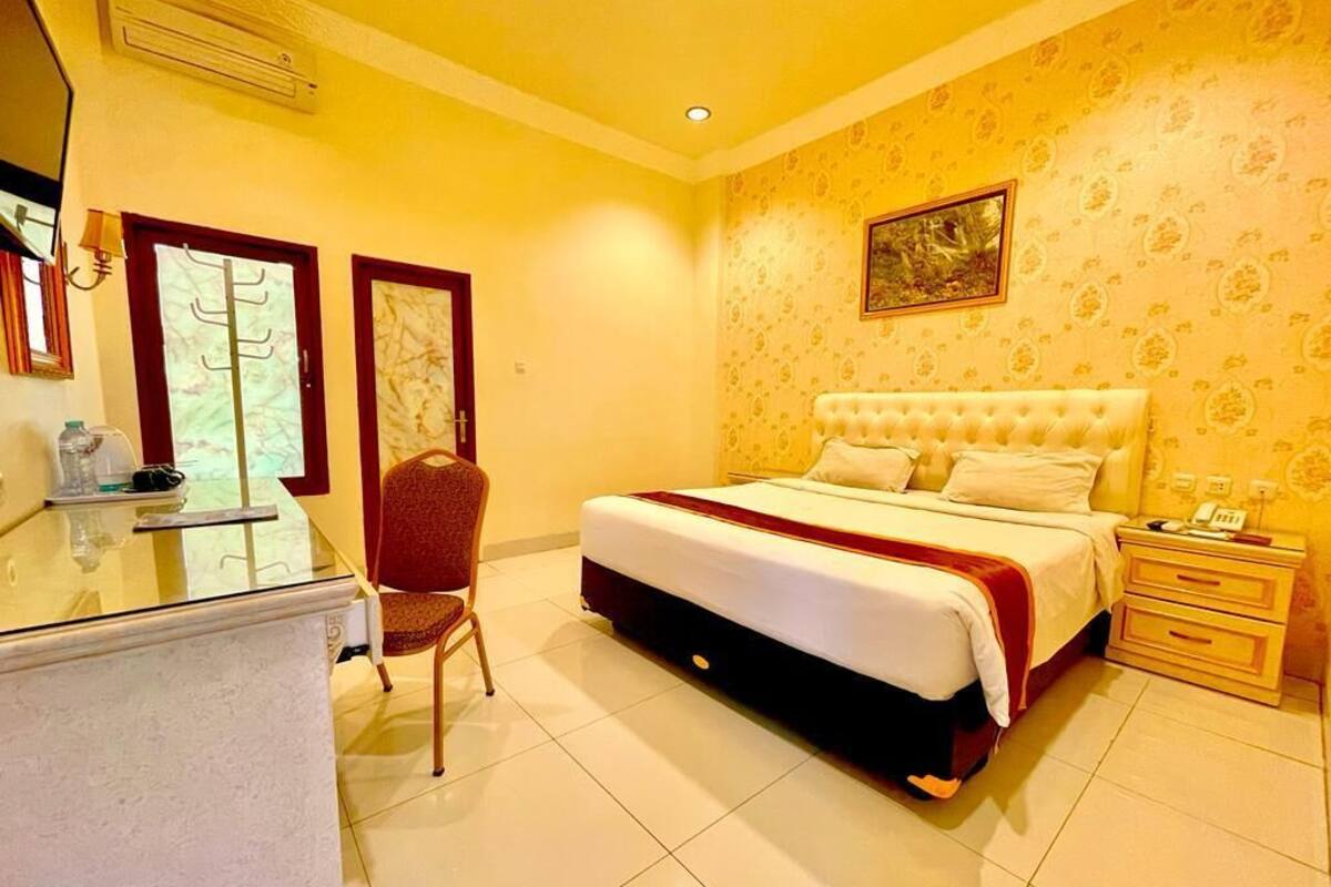 A hotel room with a large bed, a desk, and a chair.