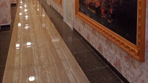 Un pasillo con piso pulido, papel tapiz estampado y cuadros enmarcados en las paredes.