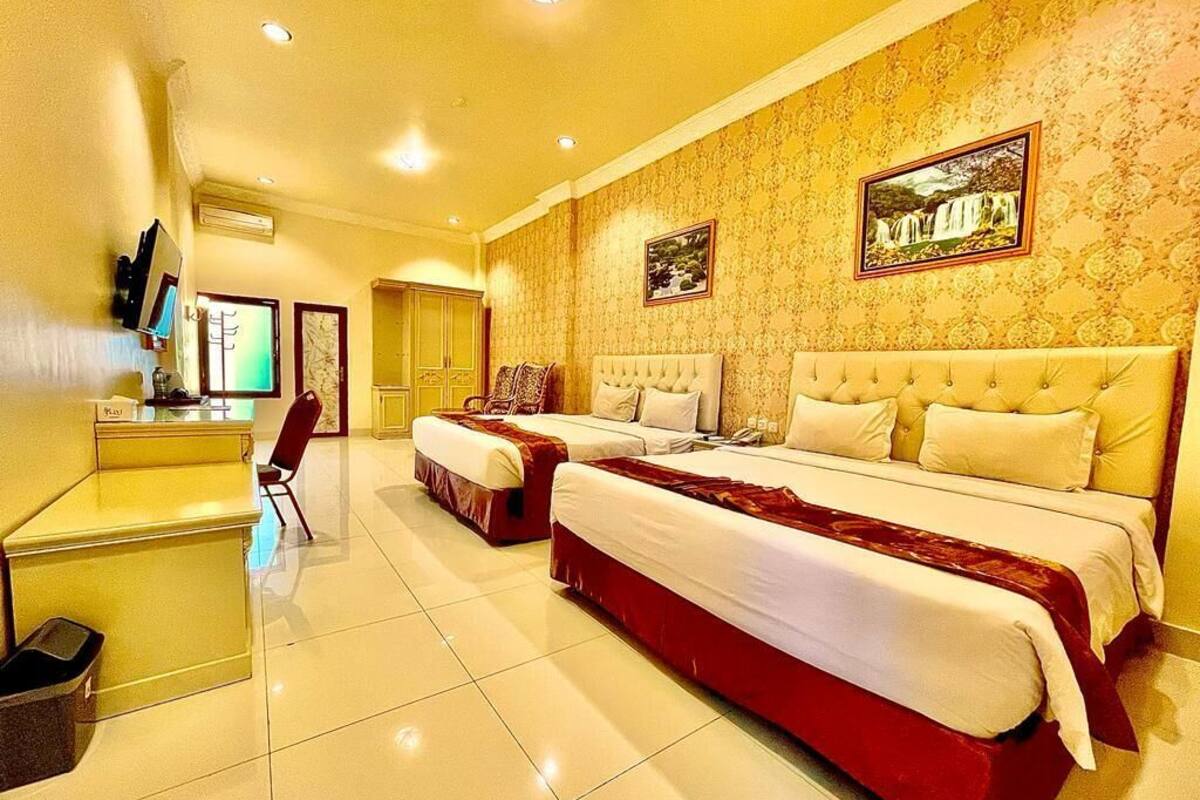 A hotel room with two beds, a desk, and a TV.