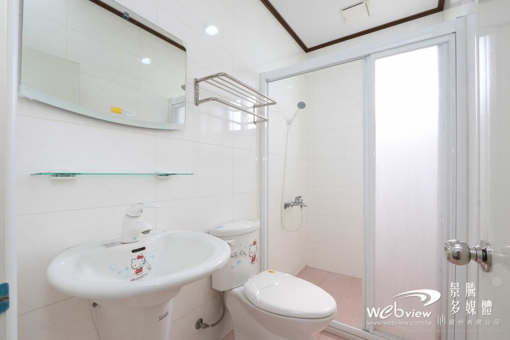 Un baño con lavamanos blanco, inodoro y cabina de ducha de vidrio.