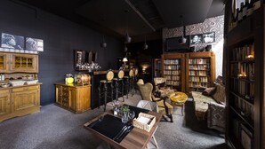 A cozy, well-lit room with a dining table, chairs, a sofa, and a bookshelf filled with books. - Hotel Dal Kielce (Kielce)