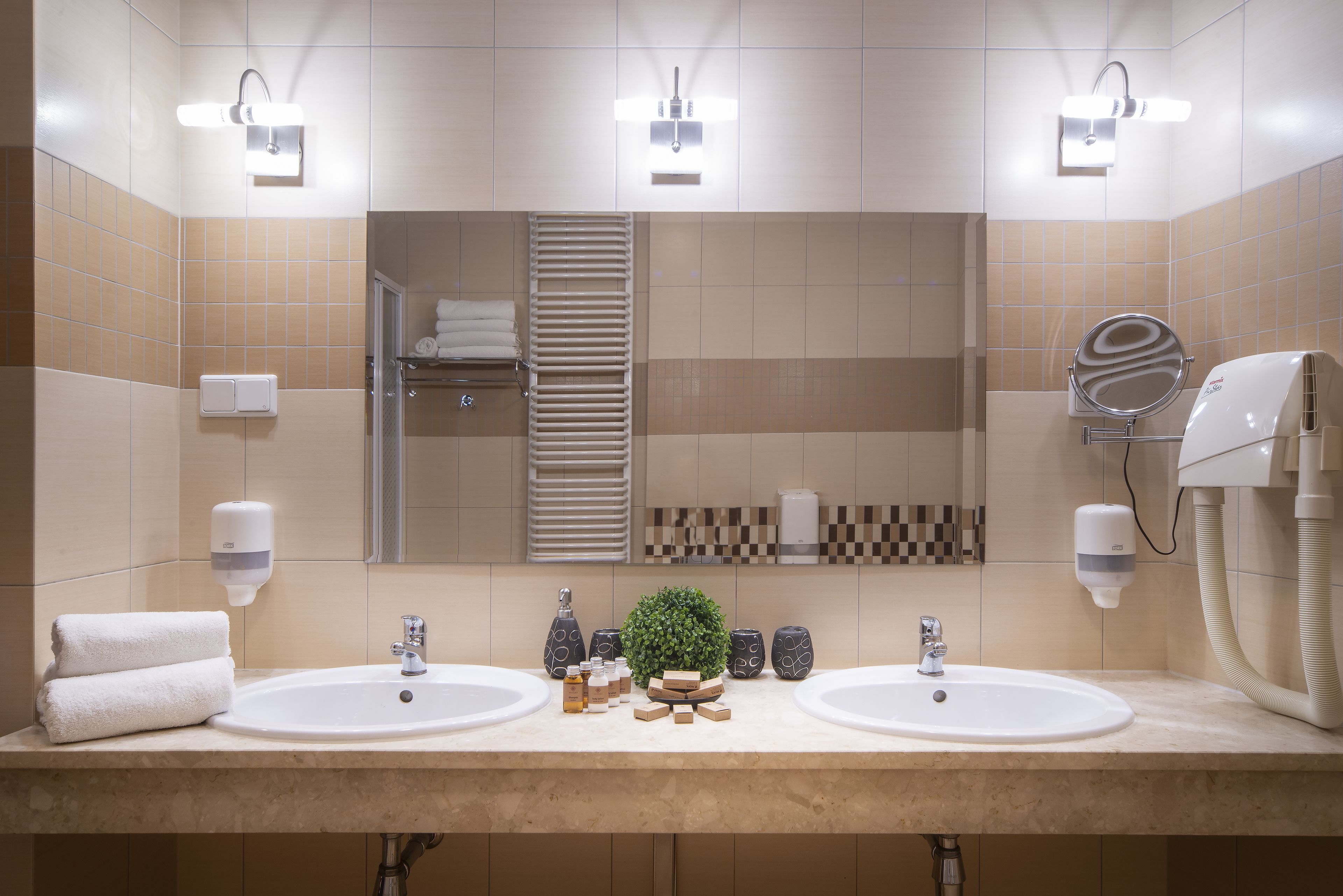 Een moderne badkamer met twee wastafels, een grote spiegel en een handdoekhouder.