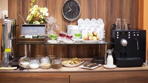 A breakfast buffet area with a clock, coffee machine, and various food and drink options. - Hotel Dal Kielce (Kielce)