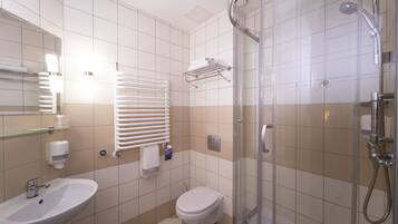 Un baño moderno con ducha de vidrio, un lavamanos blanco y un inodoro.