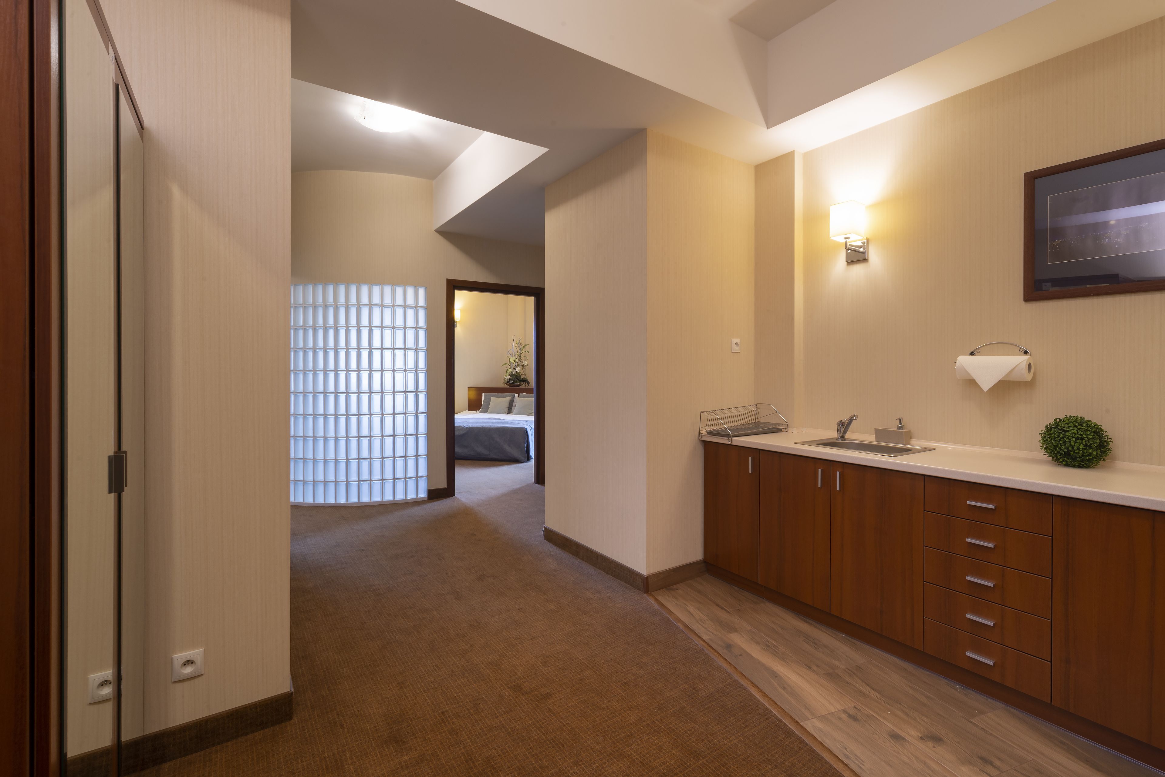 A hotel room with a wooden cabinet, a sink, and a framed picture on the wall.