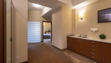 A hotel room with a wooden cabinet, a sink, and a framed picture on the wall.