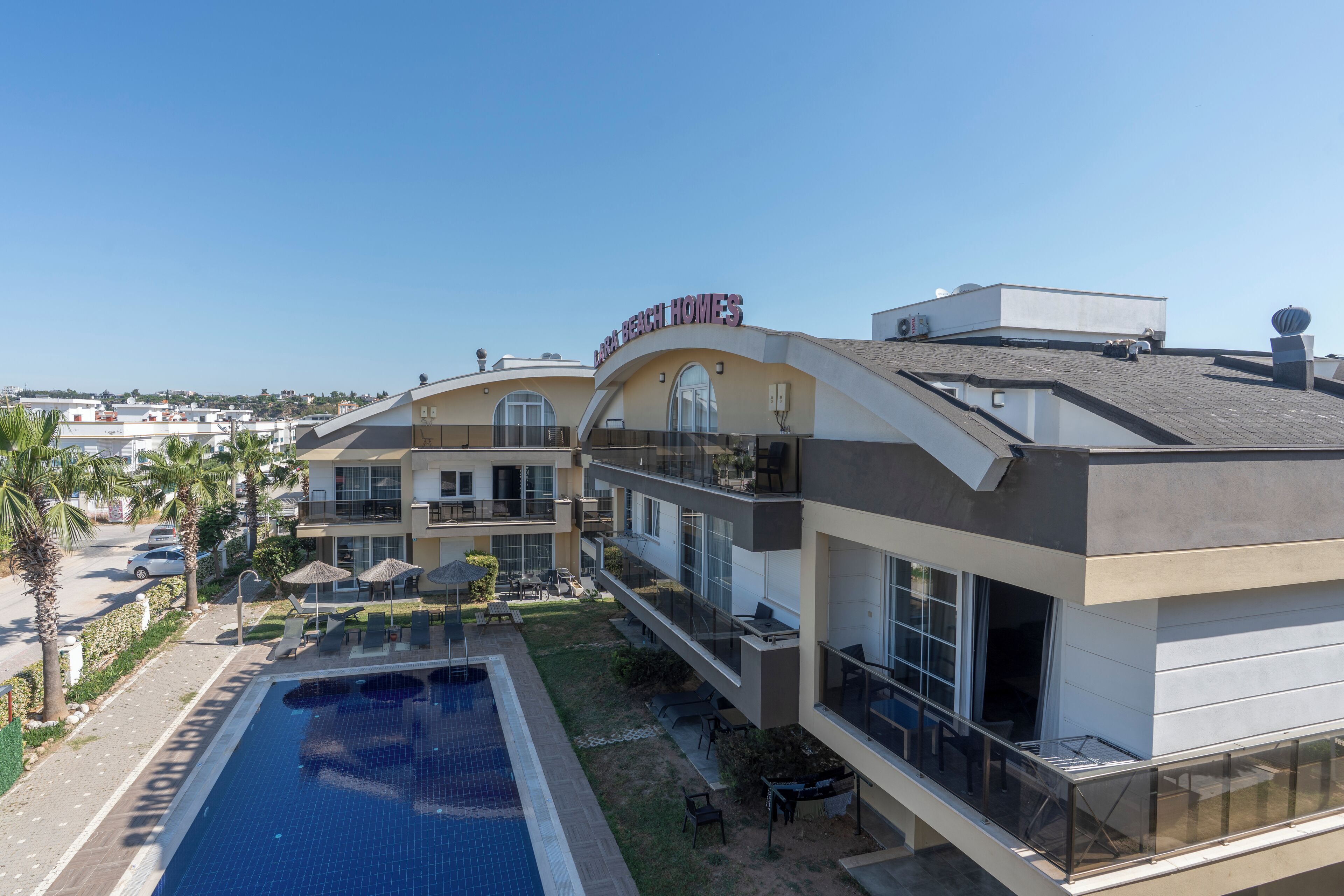 A hotel with a swimming pool, outdoor seating, and a clear view of the surrounding area.