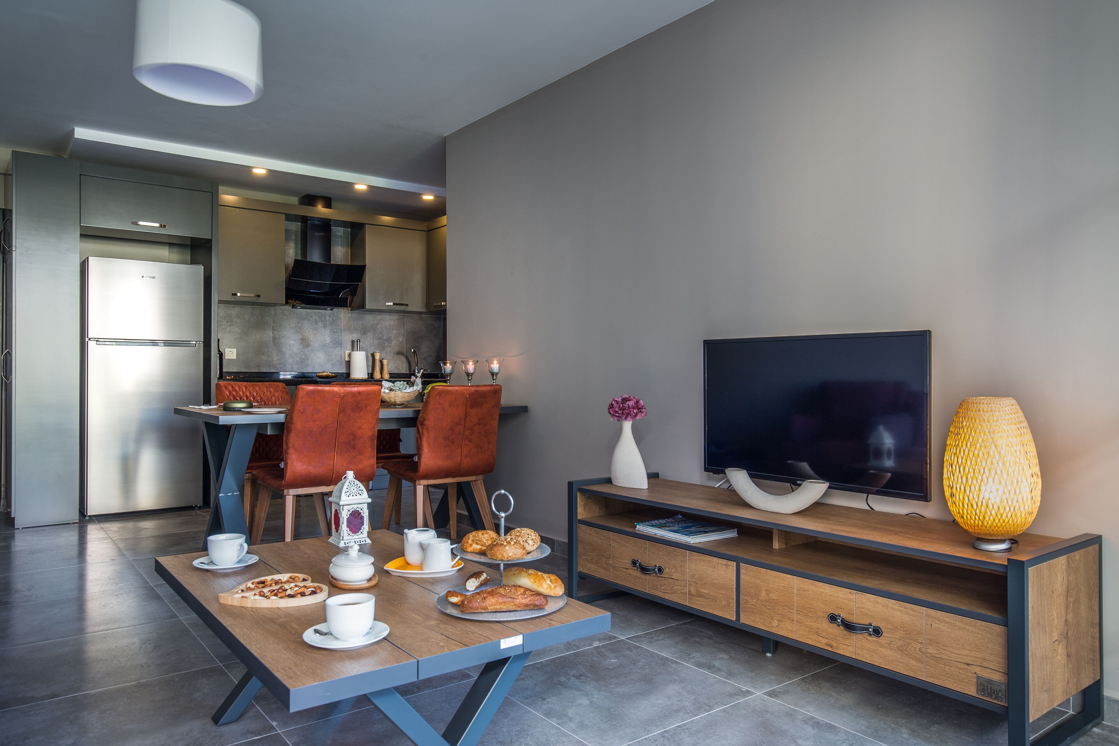 A modern living room with a dining area, a flat-screen TV, and a wooden cabinet.