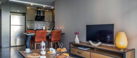 A modern living room with a dining area, a flat-screen TV, and a wooden cabinet.