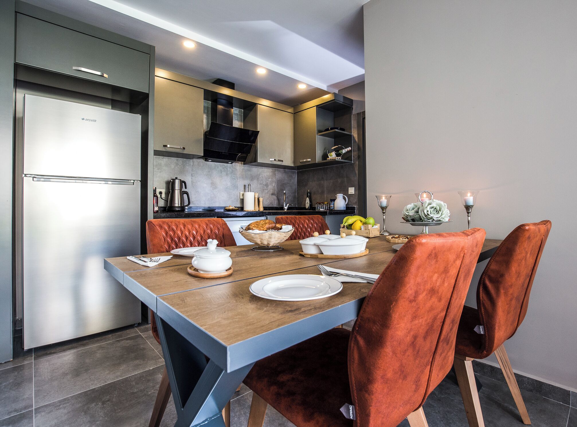 A modern kitchen with a built-in refrigerator, a dining table with chairs, and a kitchen counter with various appliances and items.