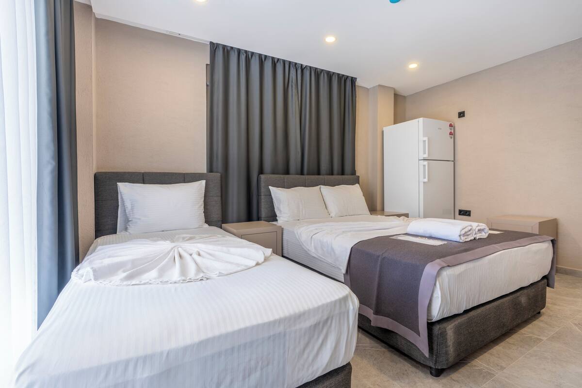 A hotel room with two beds, a wardrobe, and a refrigerator.