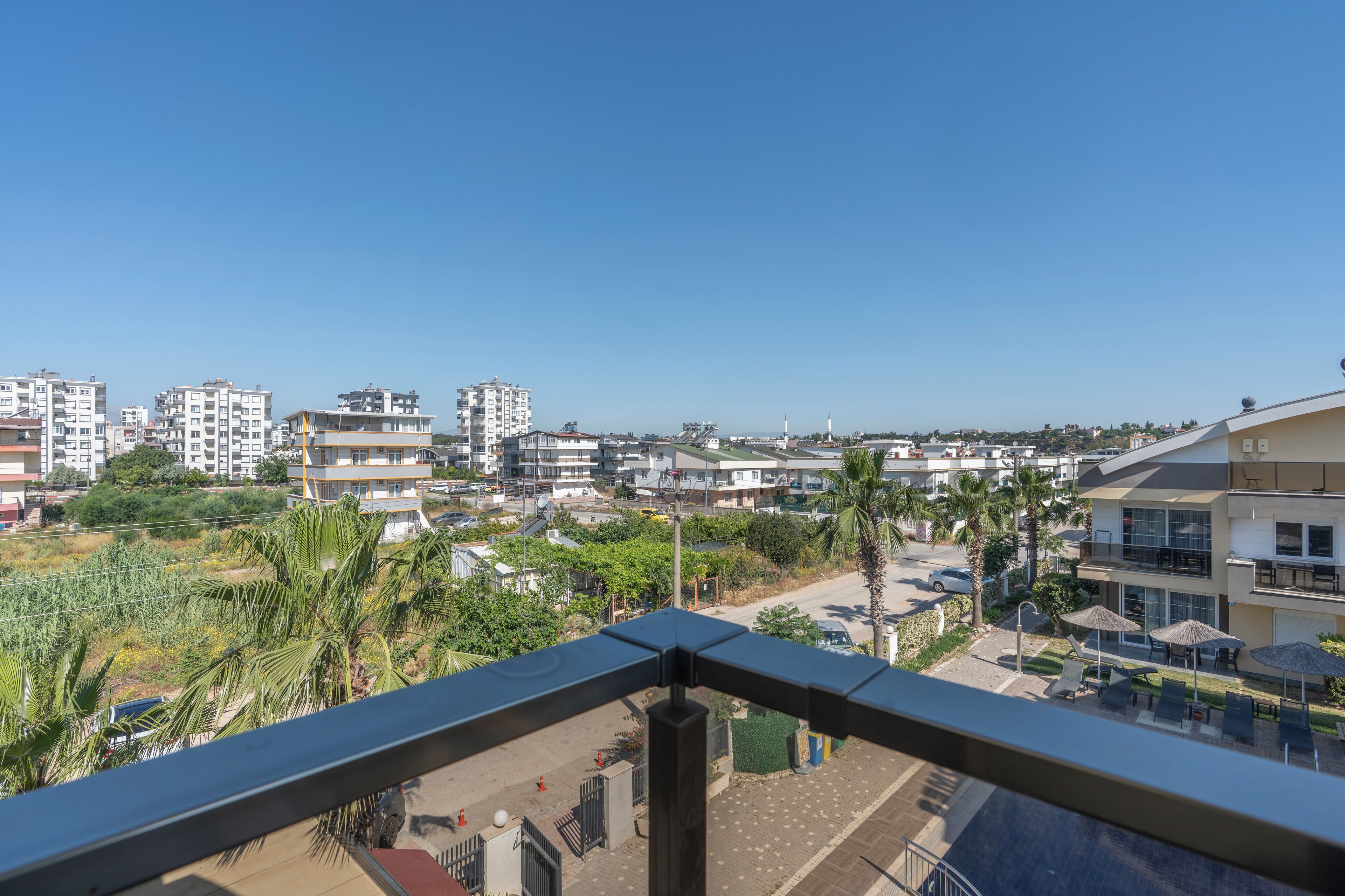 A balcony with a view of a residential area, including buildings and palm trees.